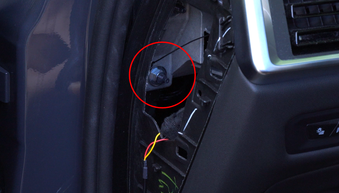 Black ground cable eyelet securely fastened to bare metal chassis bolt near vehicle fuse box